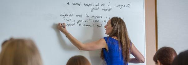 Faculty member writing on white board